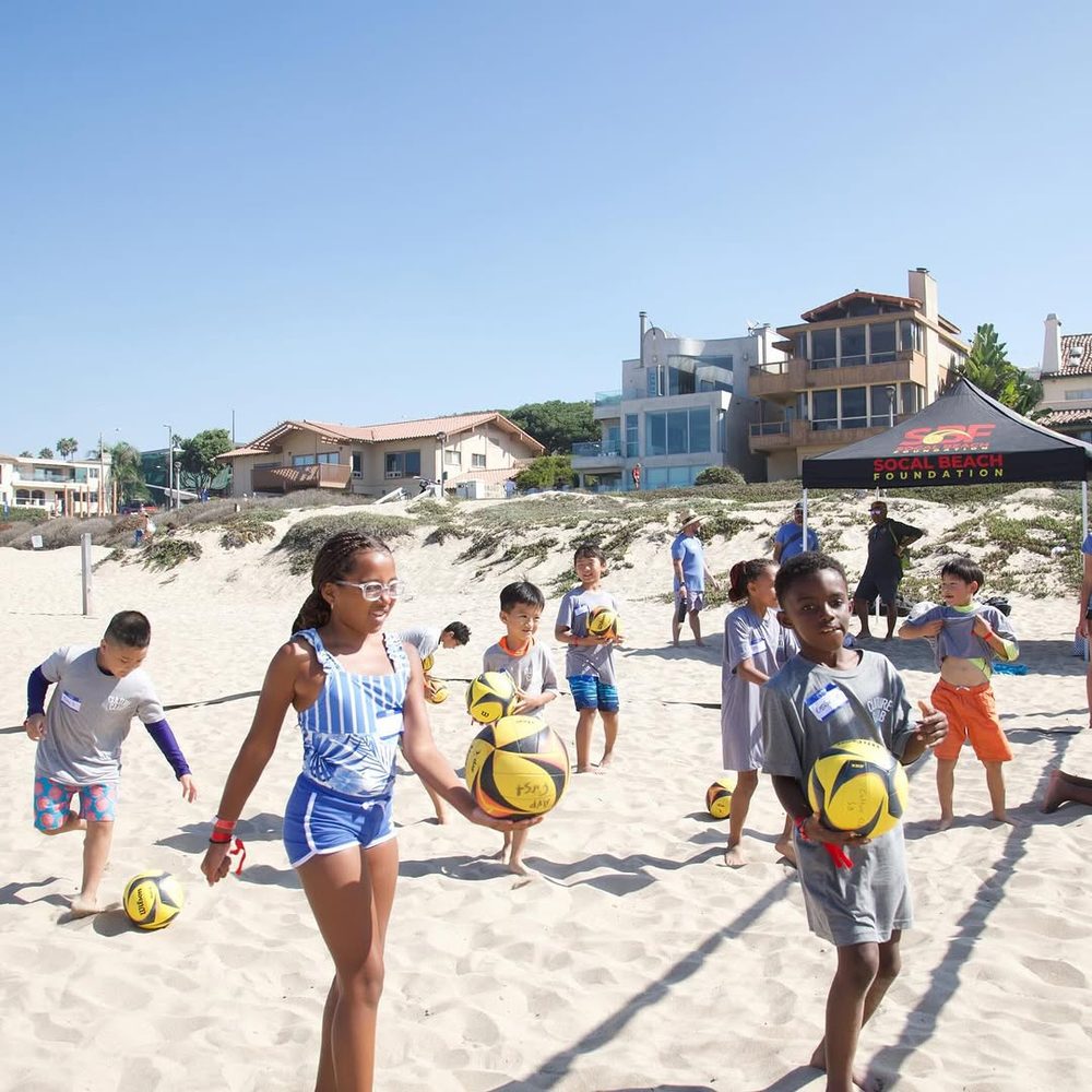 Kids holding volleyballs at an SBF youth clinic on the sand