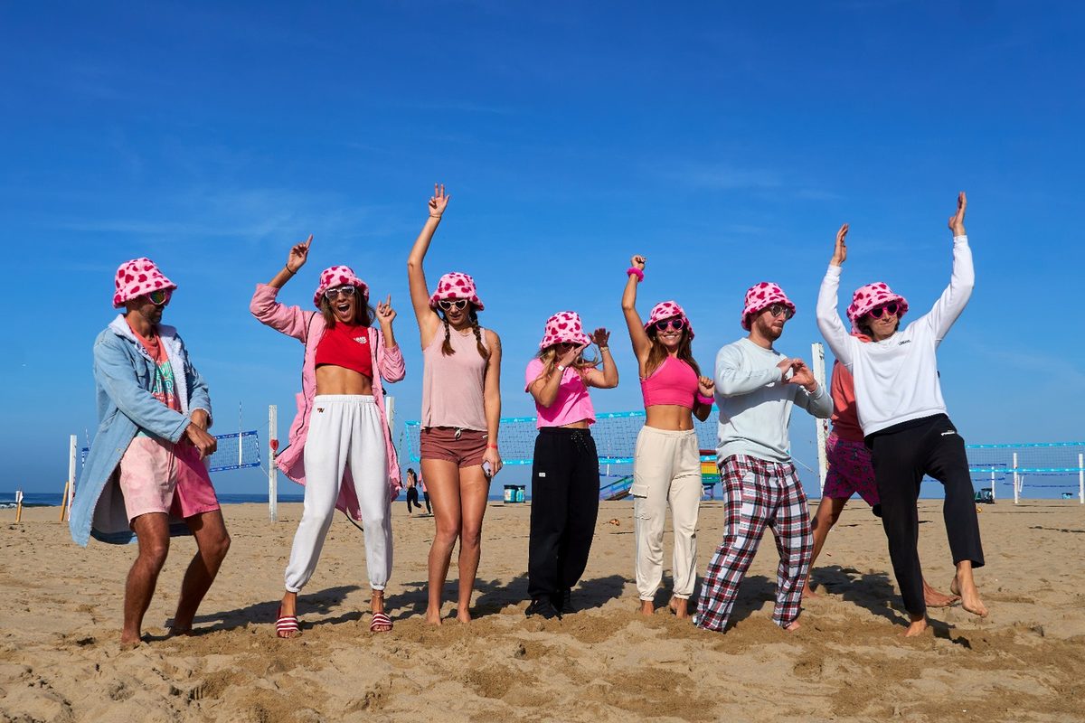 Players in matching pink bucket hats celebrating on the sand